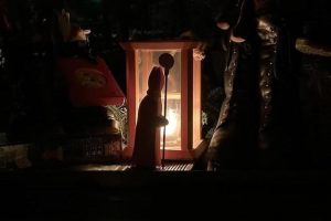 Eine Nikolausfigur vor einer Laterne im Dunkeln. Mit Süßigkeiten gefüllte Schuhe