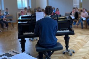Kantor am Flügel. Kinder Singen.