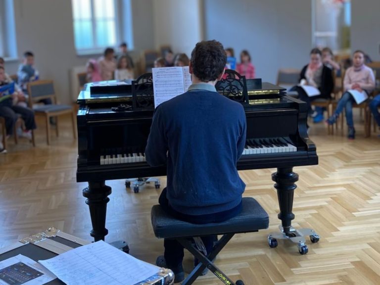 Kantor am Flügel. Kinder Singen.